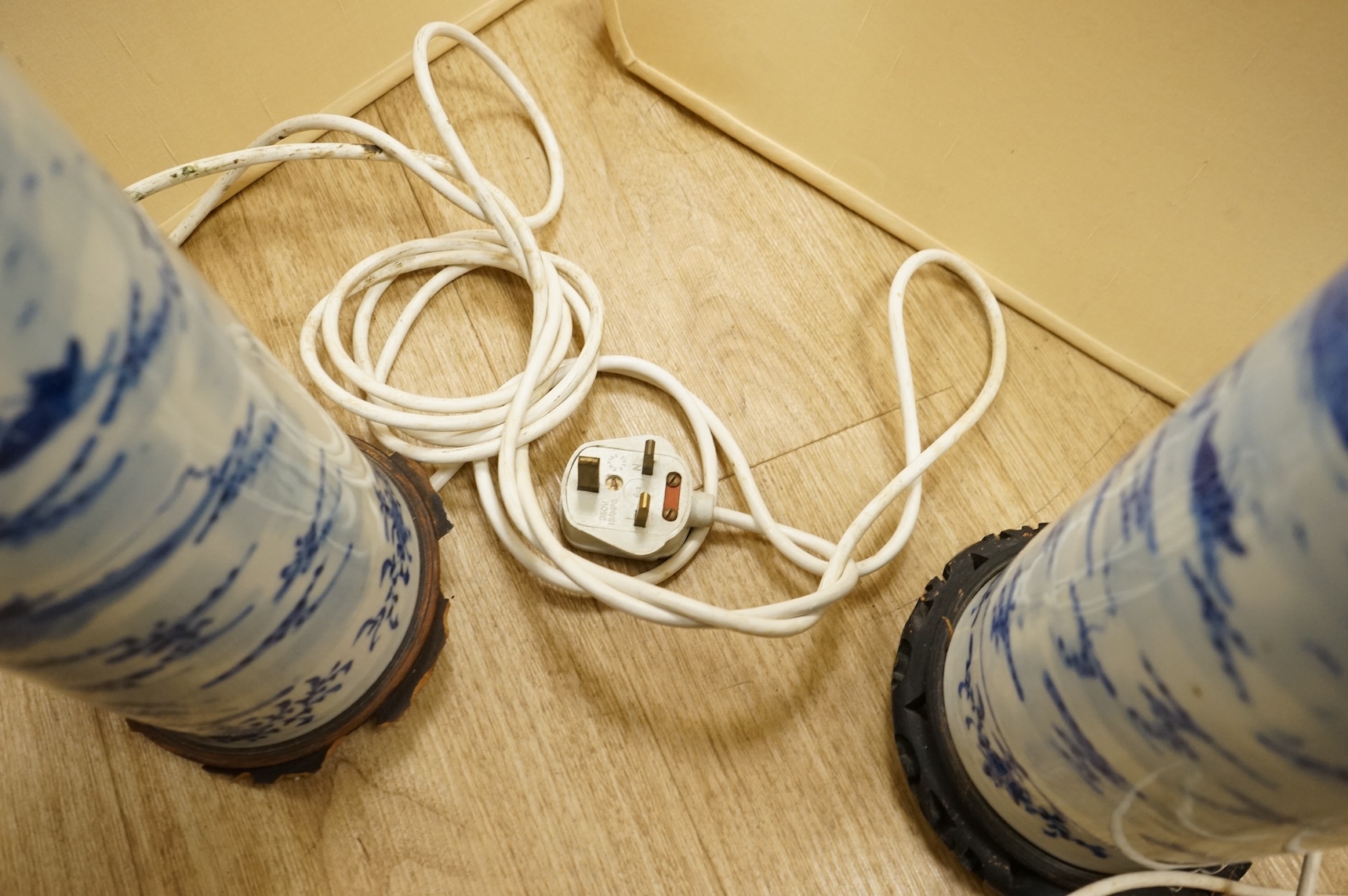 A pair of tall Chinese blue and white ‘landscape’ sleeve vases, c.1900, drilled and mounted as lamps with shades, 39cm high excluding the fitting